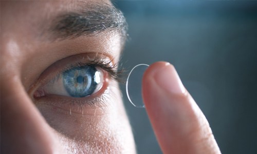 Jeune homme plaçant une lentille de contact sur son oeil